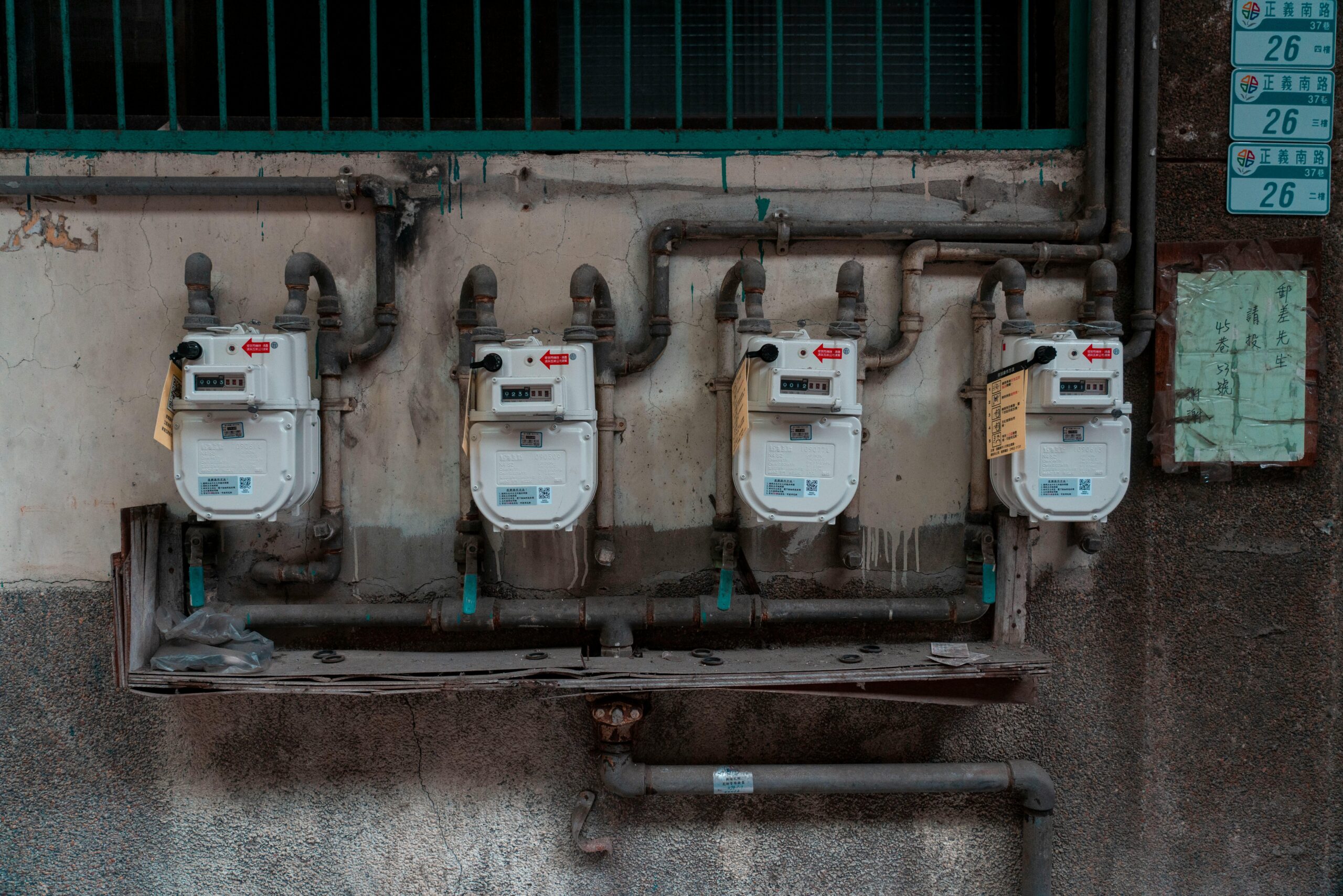 Row of gas meters mounted above pipes on an exterior wall